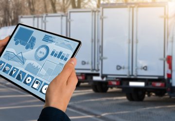 manager,with,a,digital,tablet,on,the,background,of,trucks. manager,with,a,digital,tablet,on,the,background,of,trucks.